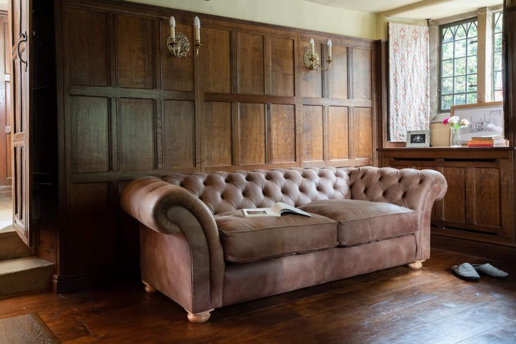 Brown leather Chesterfield sofa in a dark oak panelled room