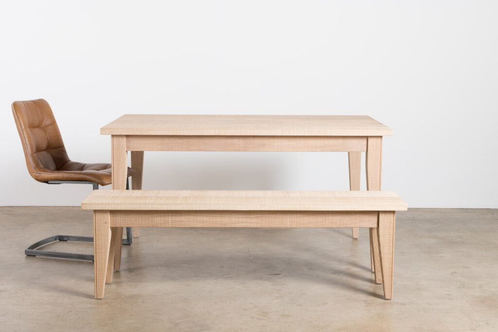 A solid oak table and bench with a leather chair