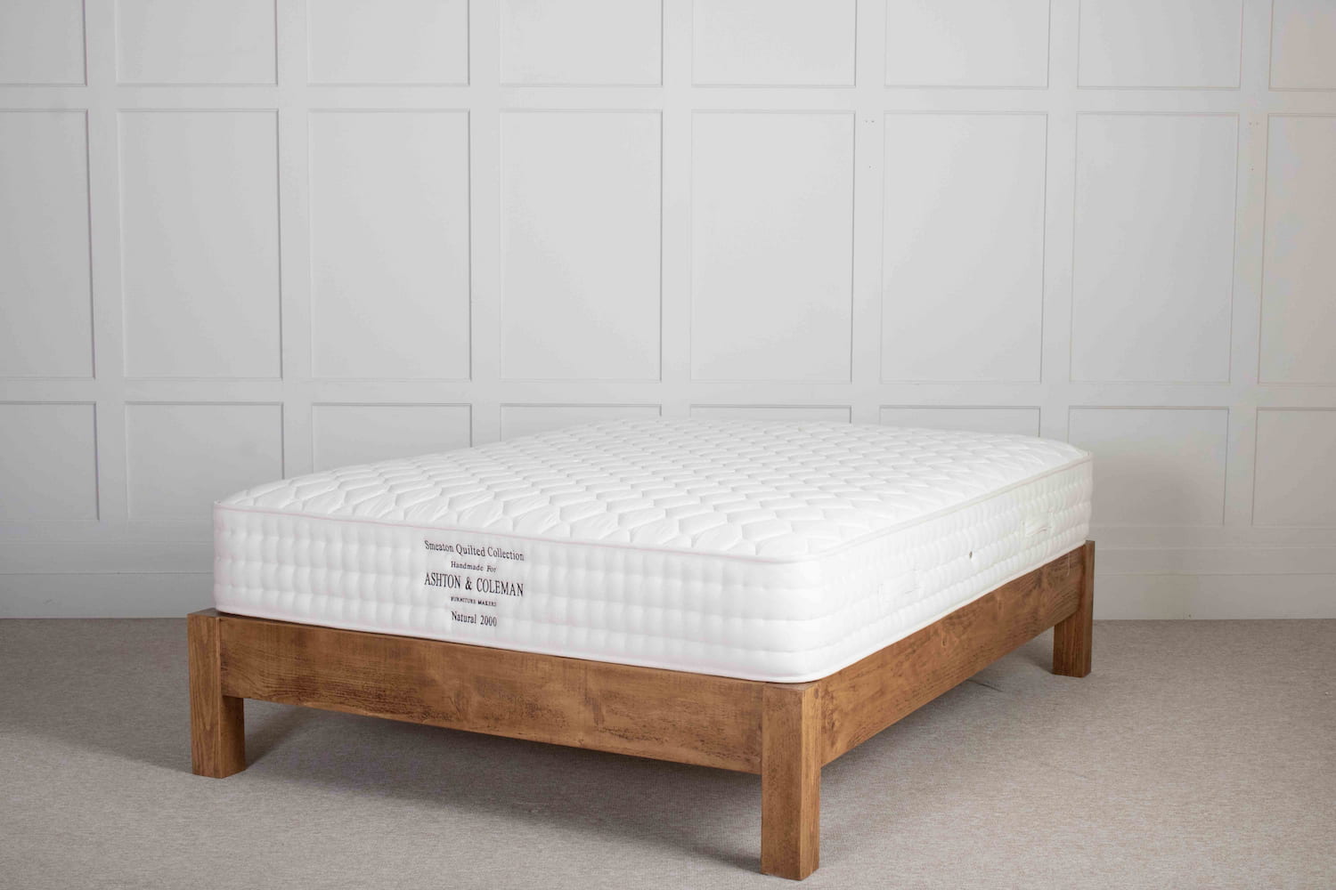A bed frame made with chunky solid wood with solid wood bed slats.The bed has a natural British made mattress on top