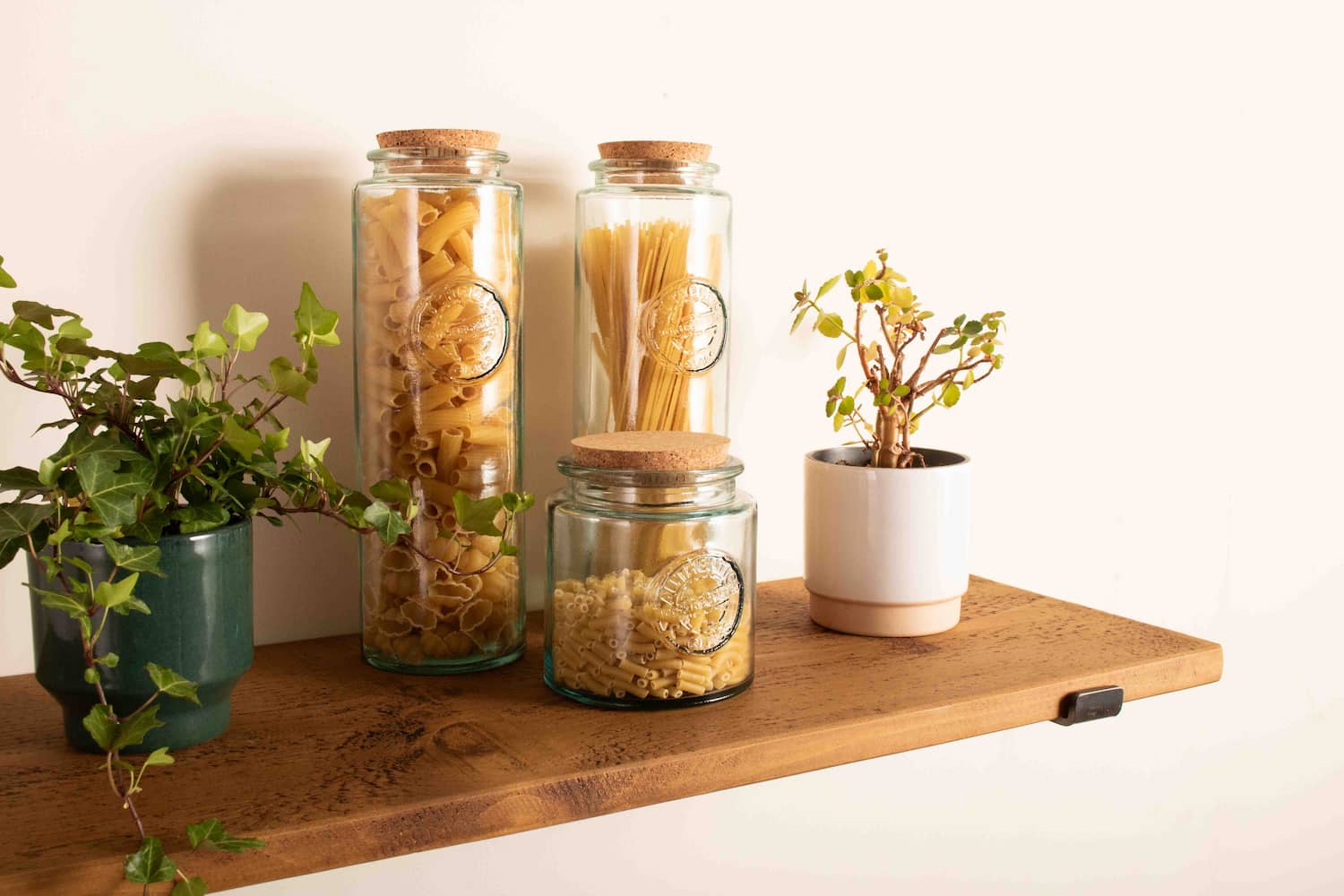 a rustic pine shelf is shown with glass storage jars and plants on display